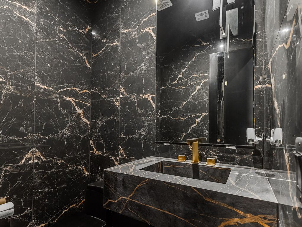 Sophisticated powder room with black marble and gold accents in a modern transitional home