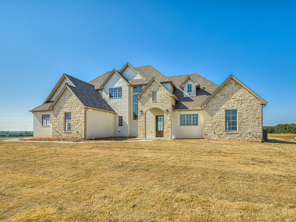 Front exterior of a large stone traditional home with gabled roof.