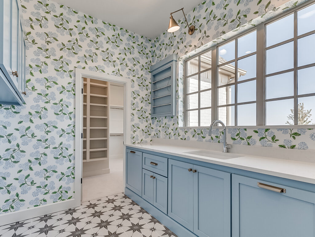 Floral wallpaper and blue cabinetry in a traditional home pantry.