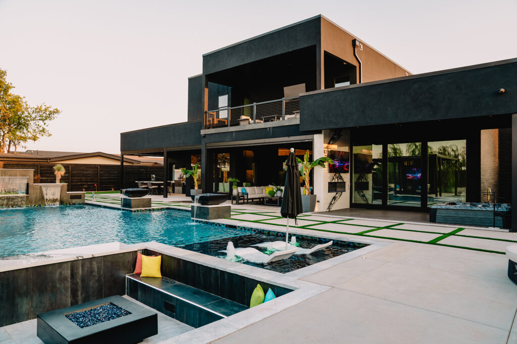 Modern backyard oasis with pool, sunken lounge, and sleek black exterior, featured in Oklahoma luxury homes.