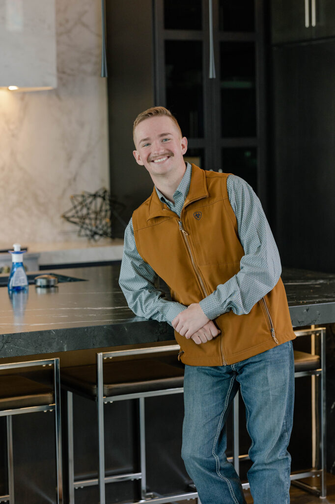 Grant Williams, client management specialist at Huffman Custom Homes, an Oklahoma Home Builder, leaning on a kitchen island.