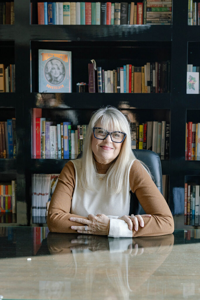Charissa Smith, administrator at Huffman Custom Homes, a leading Oklahoma Home Builder, sitting in front of a bookshelf.